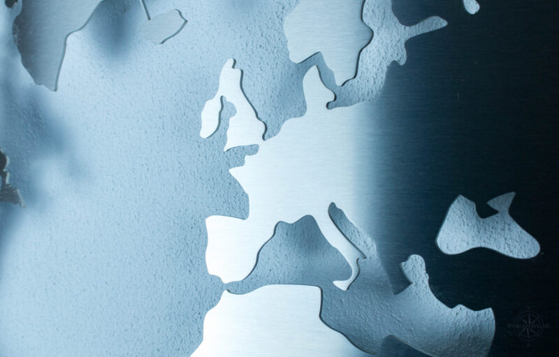 Weltkarte aus Edelstahl vor einer weißen Wand (Ansicht Detail)