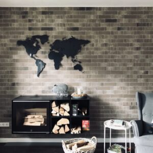 Anthrazite Weltkarte in einem Wohnzimmer oberhalb eines Kamins. Es ist noch ein toller Sessel zus ehen