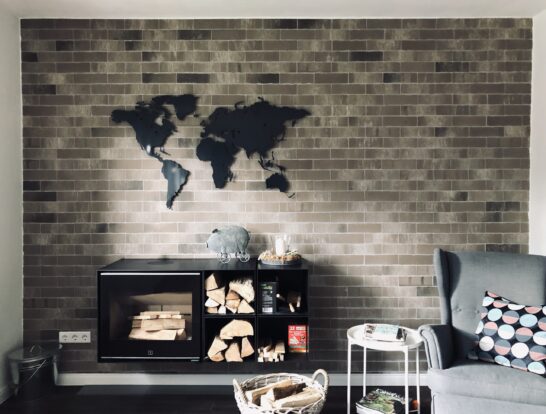 Anthrazite Weltkarte in einem Wohnzimmer oberhalb eines Kamins. Es ist noch ein toller Sessel zus ehen