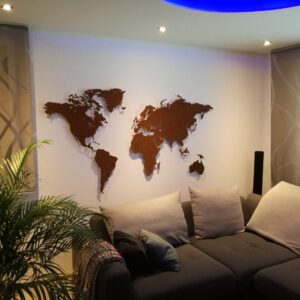 Auf dem Bild ist eine rostige Weltkarte zu sehen in einem Wohnzimmer. Sofa und ein Stück einer Pflanze ist auch zu sehen.