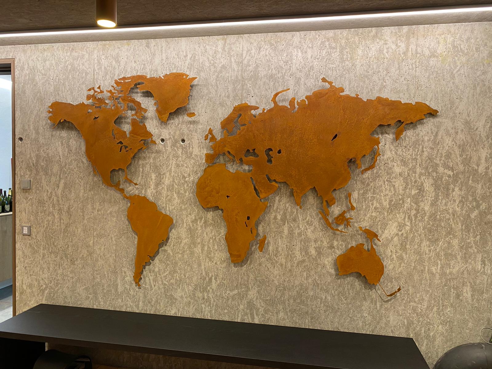 Auf dem Bild ist eine Weltkarte in einer Sonderanfertigung (extra groß) zu sehen. Sie hängt an einer betonoptik Wand.