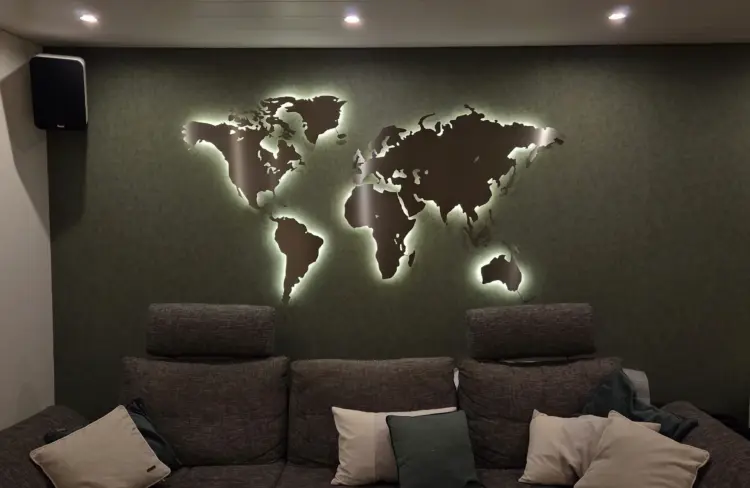 beleuchtete Weltkarte aus Metall in einem Wohnzimmer auf einer dunkelgrünen Wand