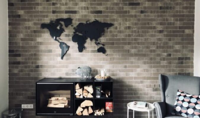 Anthrazite Weltkarte in einem Wohnzimmer oberhalb eines Kamins. Es ist noch ein toller Sessel zus ehen