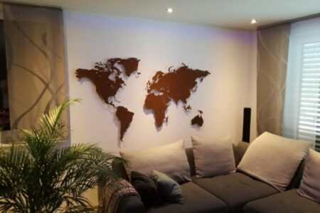 Auf dem Bild ist eine rostige Weltkarte zu sehen in einem Wohnzimmer. Sofa und ein Stück einer Pflanze ist auch zu sehen.