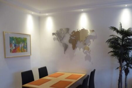 Weltkarte aus Edelstahl an einer weissen Wand in einem Esszimmer