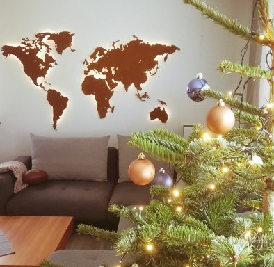 Weltkarte rostig aus COR-TEN Stahl in einem Wohnzimmer. im Vordergrund steht ein Weihnachtsbaum